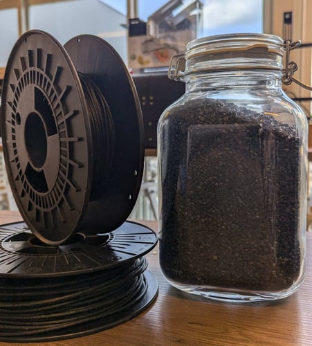 Carbon fiber filament next to carbon fiber plastic pellets